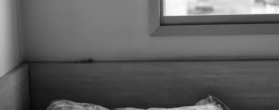 grayscale photo of person lying on bed